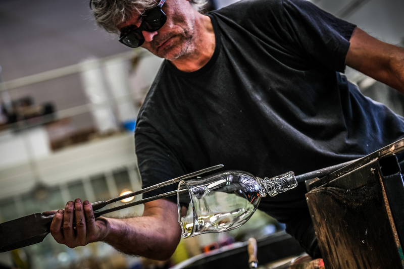 A man pinching hot glass as he is glassblowing representing the arts on Vashon as a part of the culture of the island.