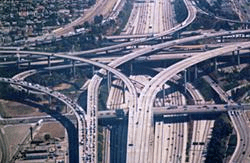 Aerial view of a complex multi-level highway interchange with looping ramps and overpasses in an urban area.