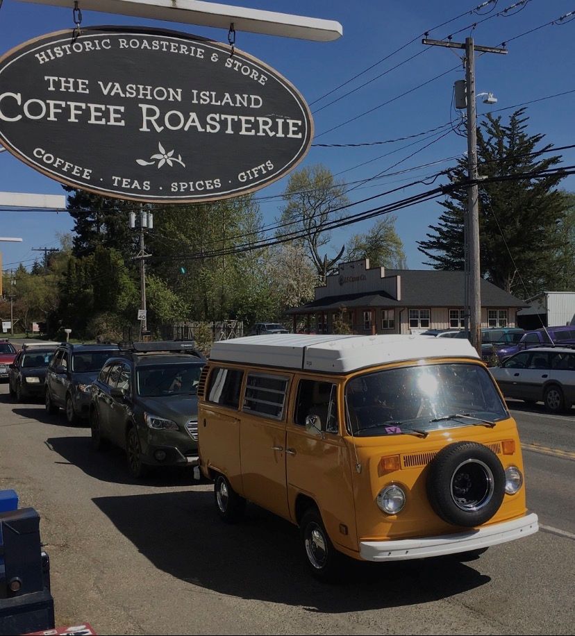 Roasterie sign | Vashon Maury Island Oval sign for The Vashon Island Coffee Roasterie hangs over a yellow vintage Volkswagen bus parked on a sunny street.