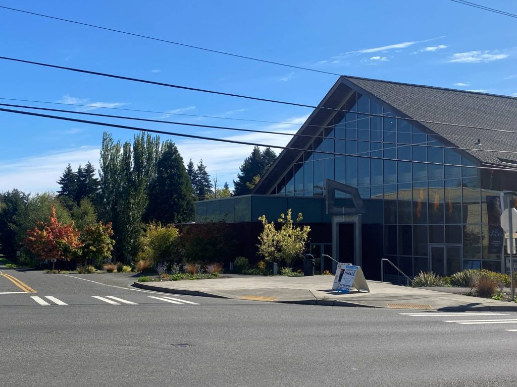 Vashon Center For The Arts | Vashon Maury Island Modern glass-fronted building with a steep triangular roof, trees in front, and power lines across a blue sky.
